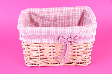 Wicket basket with pink fabric and bow, on color background