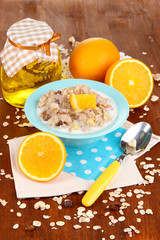 Useful oatmeal in bowl with fruit on wooden table close-up
