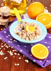 Useful oatmeal in bowl with fruit on wooden table close-up