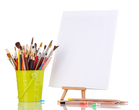 Small easel with sheet of paper with art supplies isolated
