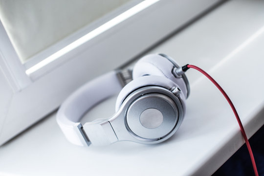 White headphones with red wire on the sill