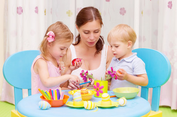Obraz na płótnie Canvas Mother with kids paint Easter eggs