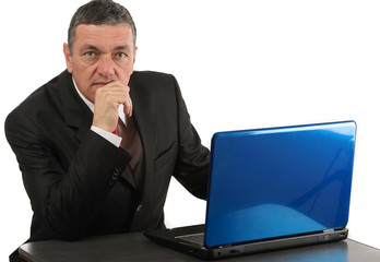 Aged businessman sitting at desk with a laptop isolated on white