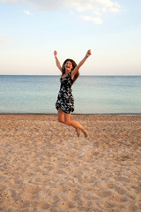 Happy woman jumping on beach. Summer holidays.