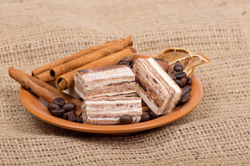 Sweets, cinnamon, nuts and coffee beans on a saucer, on burlap b