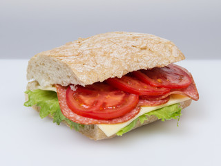 big sandwich with salami cheese tomato and salad leaves