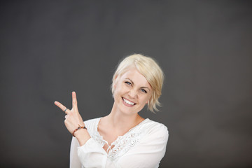 lachende blonde frau zeigt zwei finger