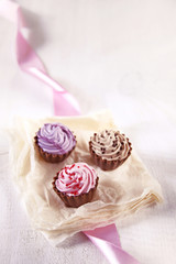 drei pralinen in cupcake form, rosa, lila und braun