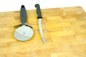pizza wheel and small knife on chopping board