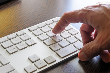 A senior man is using the numeric keyboard of his computer