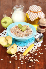Useful oatmeal in bowl with fruit on wooden table close-up