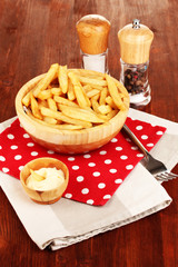 French fries in bowl on wooden table close-up