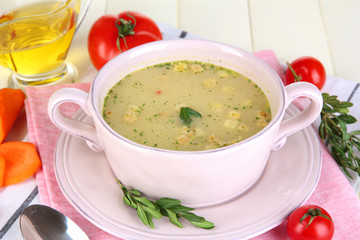 Nourishing soup in pink pan on wooden table close-up