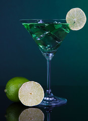Green cocktail with lime on dark green background