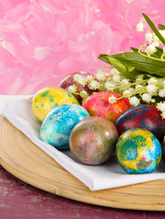 Easter eggs on wooden plate on napkin with flowers close-up