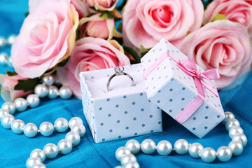 Rose and engagement ring on blue cloth