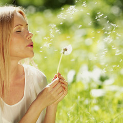 girl blowing on a dandelion