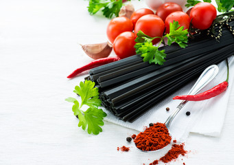 Uncooked black pasta with tomatoes, fresh herbs and spices