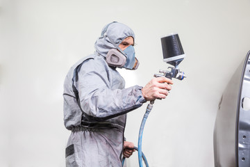 Car body painter spraying paint on bodywork parts