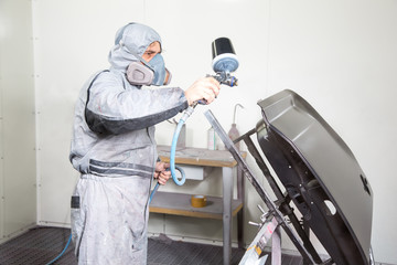 Car body painter spraying paint on bodywork parts