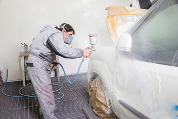 Car body painter spraying paint on bodywork parts