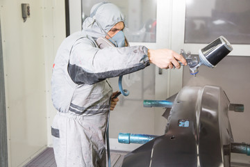 Car body painter spraying paint on bodywork parts