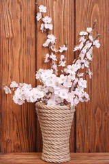 Flowering apricot branch in a vase on a wooden boards background