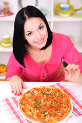 Beautiful girl with delicious pizza on kitchen background