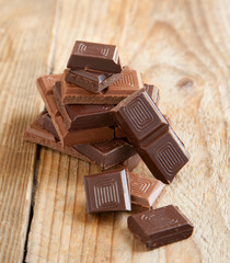 Broken chocolate bar on wooden background. Selective focus