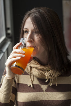 Beautiful Young Woman with Brown Hair Drinking Glass of Mango Ju