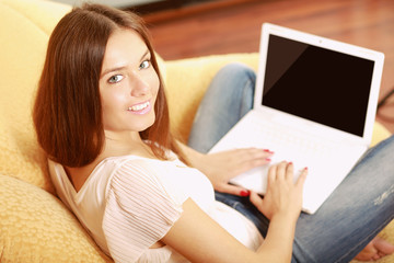 A woman working on a laptop sitting on a sofa