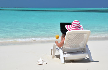 Girl with a laptop on the tropical beach. Exuma, Bahamas