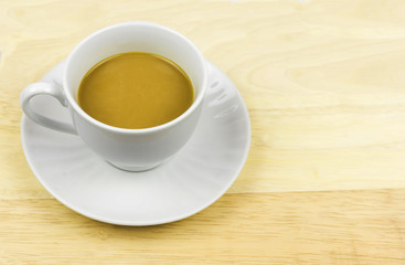 A cup of coffee with creamer on chopping board
