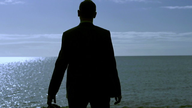 Businessman silhouette standing on a sunny beach in the morning,