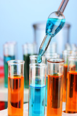 Laboratory pipette with drop of color liquid over glass test