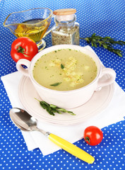 Nourishing soup in pink pan on blue tablecloth close-up
