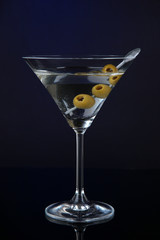 Martini glass with olives on dark blue background