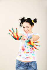 Young pretty painter with hands in paint, on gray background