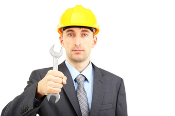 Young businessman in helmet with wrench isolated on white.