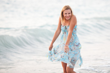 Fototapeta na wymiar Young beautiful woman standing on beach near waves