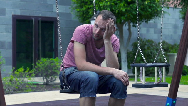 Sad man sitting on a swing, slow motion shot at 240fps 