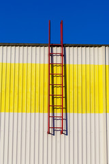 Red ladder on a white-yellow wall.