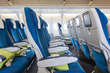 Comfortable seats in cabin of aircraft with screens in chairs