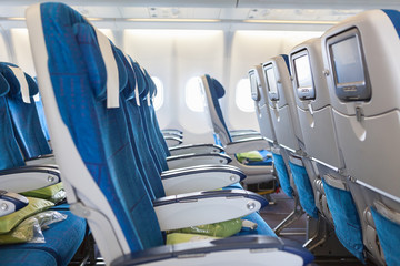 Empty comfortable chairs in cabin of aircraft with screens
