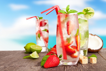 Fresh summer drinks on wooden table with blur sea background