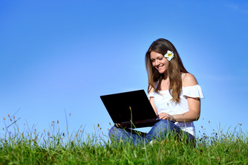 Smiling girl using laptop in nature