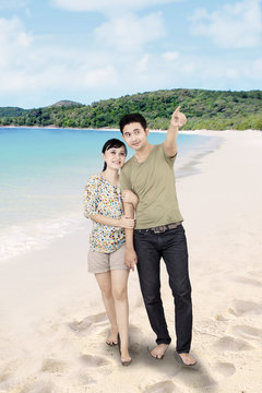Asian boyfriend pointing at beach