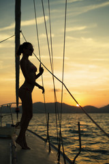 girl standing on a yacht at sunset