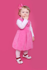 Full length portrait of funny little girl standing over pink bac