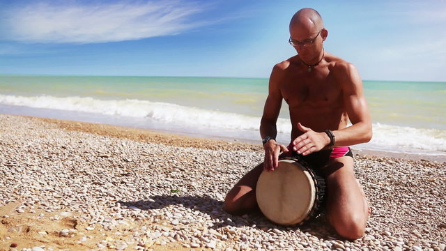 Djembe Drum Player beat rythm on the lonely beach
